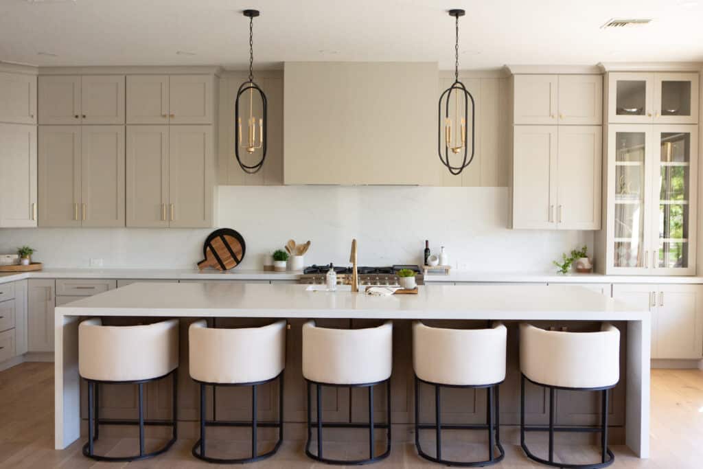 Modern kitchen with neutral tones, large island, and black pendant lighting in a staged home in Chandler, AZ.